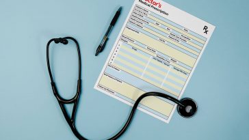 A mockup image of a doctor's prescription pad on a white background. The pad is open to a blank prescription with a stethoscope and medical tools placed on top of it.