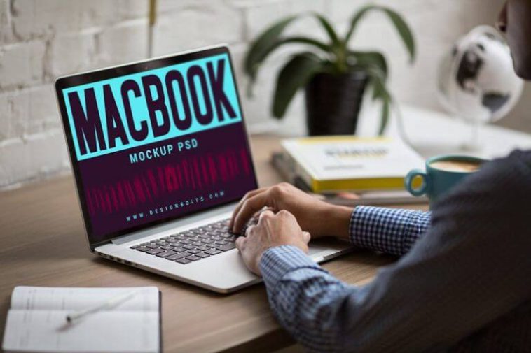 3/4 View Man Working on MacBook on Office Table Mockup