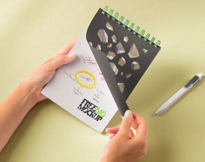 Free Hands Holding Spiral Notepad Mockup PSD